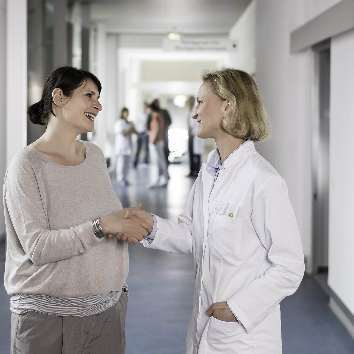 Eine Ärztin spricht mit einer Patientin und reicht ihr die Hand